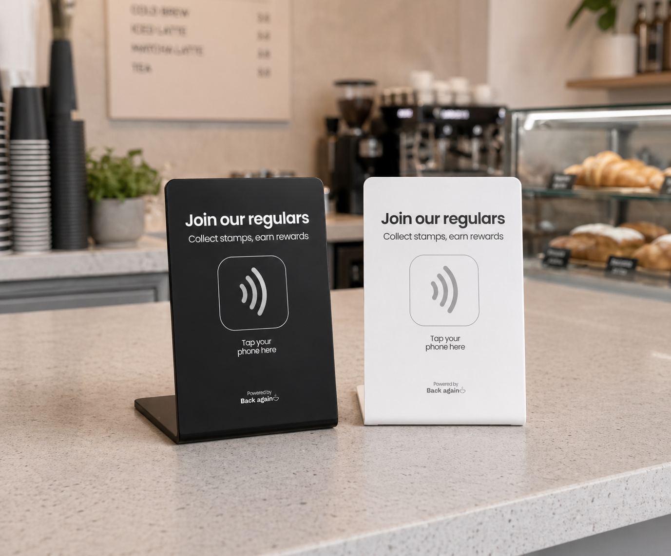 Back Again NFC counter signs in matte black and crisp white sitting on a café counter
